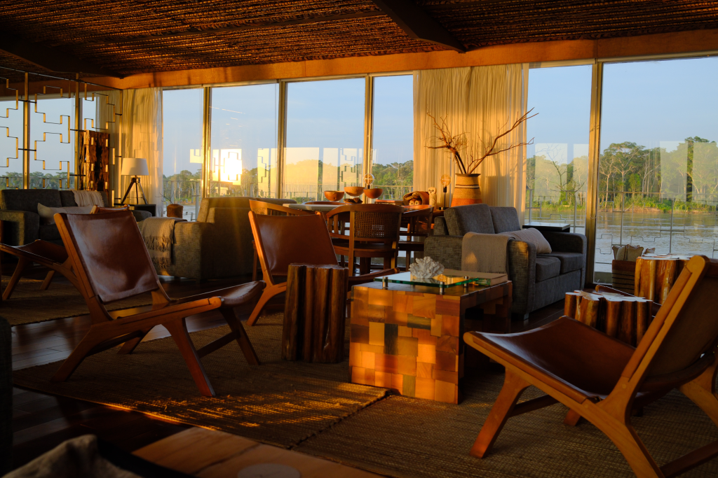 Luxury lounge interior aboard Delfín Amazon Cruises overlooking the Peruvian Amazon River at sunset