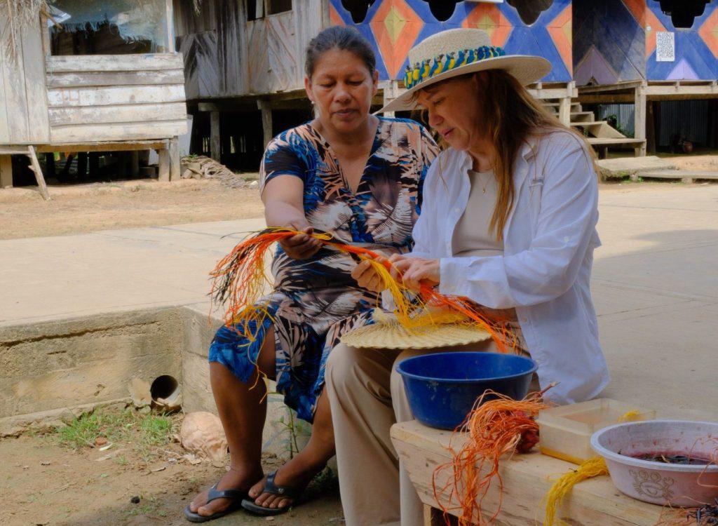 Lizzy learning traditional fiber weaving techniques with an Amazonian artisan during a cultural visit