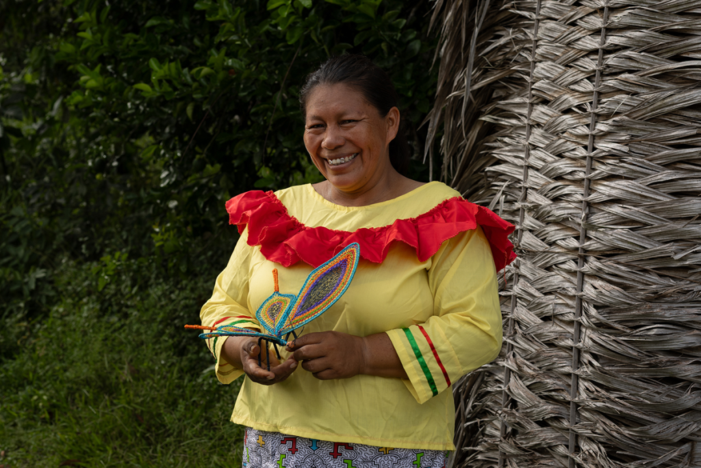 Amazonian artisan smiling while holding a handcrafted woven butterfly made from natural fibers