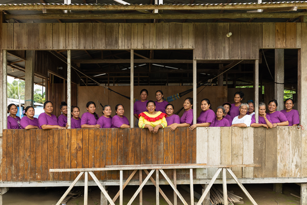 Amazonian women artisans standing together in a traditional wooden house in Peru