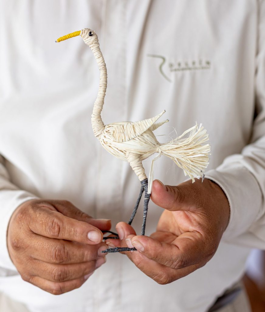 Handcrafted woven bird made from natural fibers held by a guide from Delfín Amazon Cruises
