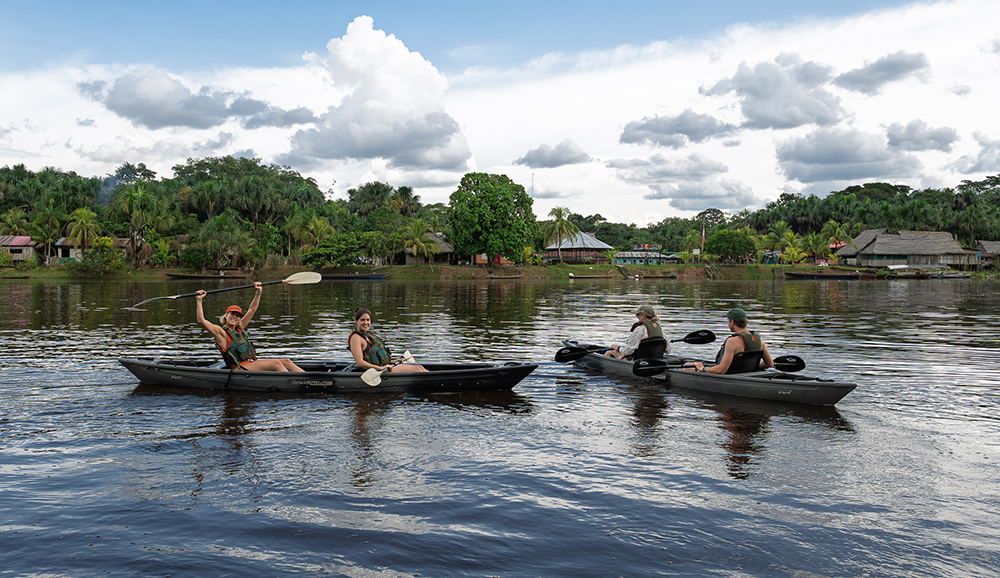 Guests kayaking on the Amazon River near a local community during a Delfín Amazon Cruises expedition in Peru