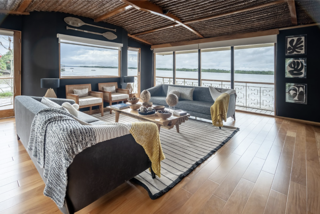 Lounge area aboard Delfín I with panoramic Amazon river views, elegant seating and warm wooden interiors