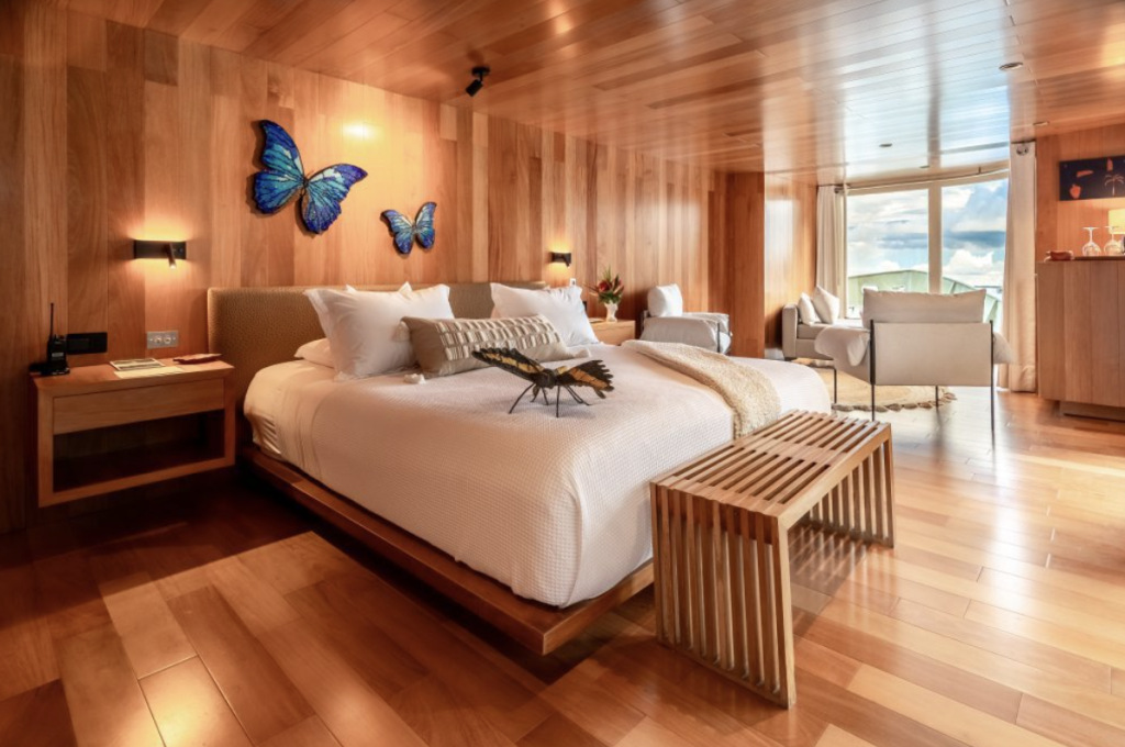 Morpho suite aboard Delfín I featuring a king bed, warm wood interiors and Amazon inspired design elements