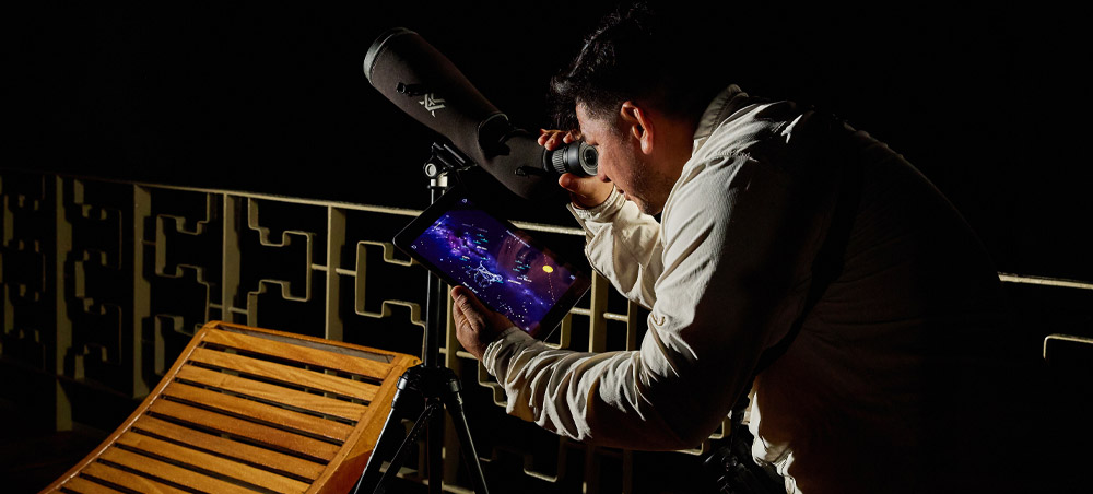 Naturalist guide using a telescope and star map aboard a Delfín vessel