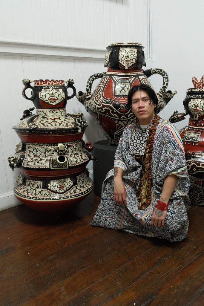Amazonian artist beside decorated ceramic sculptures at Río Corrientes