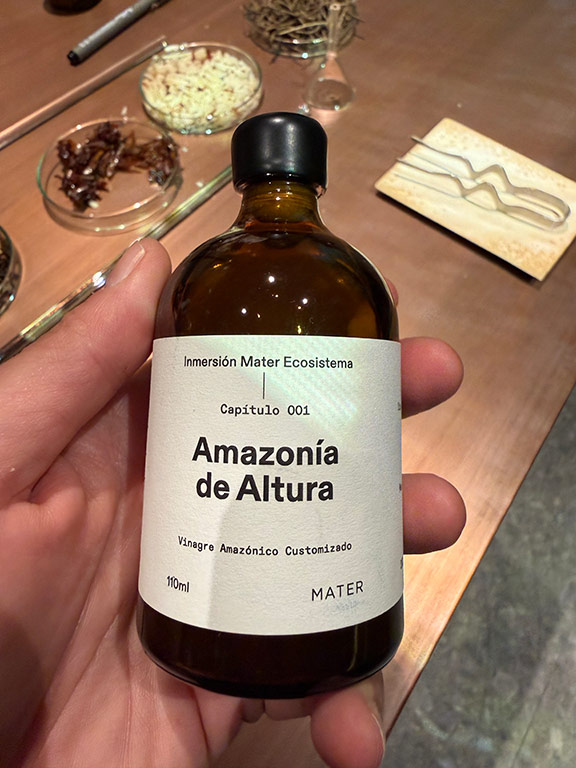 A hand holding an amber bottle labeled Amazonía de Altura personalized Amazonian vinegar.